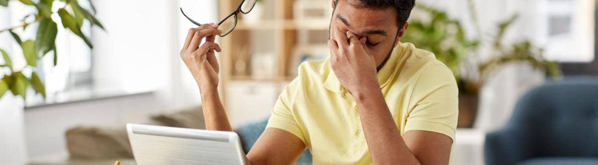 man rubbing his eyes after staring at computer screen