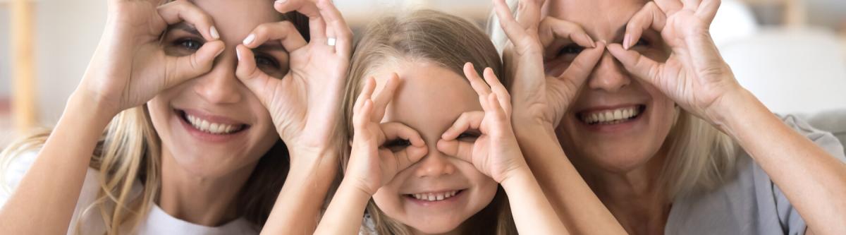 Happy kid, mother and grandmother having fun with hands at eyes, smiling faces pretending to have glasses, eye health concept